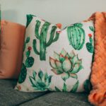 Throw Pillows - three green, orange, and white throw pillows on sofa